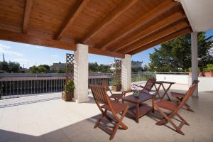 un patio con mesa, sillas y techo de madera. en Hotel Donatello en Alberobello