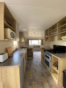 a kitchen with wooden cabinets and a stove top oven at Modern & Homley 3BR Caravan in Hastings