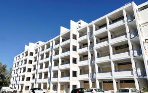a white apartment building with cars parked in front of it at Parque Mourabel, Oásis Village & Pé do Lago in Vilamoura