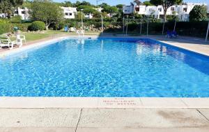 a large blue swimming pool with a sign on the curb at Parque Mourabel, Oásis Village & Pé do Lago in Vilamoura