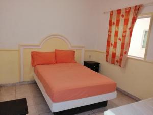 a bedroom with a bed with orange pillows and a window at Hotel Kiko in Mazatlán