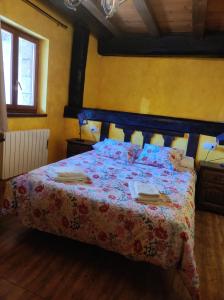 1 dormitorio con 1 cama con colcha de flores en CASA RURAL EL TOLEO, en Hoyos del Espino