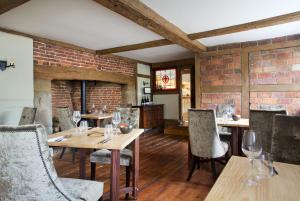 a restaurant with wooden tables and chairs and a brick wall at The Queen's Inn in Hawkhurst