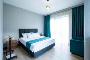 a bedroom with a bed and a blue chair at Hotel GENI Kazbegi in Stepantsminda