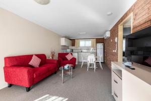 a living room with a red couch and a kitchen at Bomaderry Motor Inn in Nowra