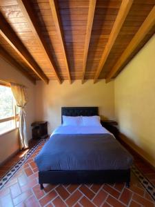 - une chambre avec un grand lit et un plafond en bois dans l'établissement BS HOTEL CAMPESTRE, à Cucunubá