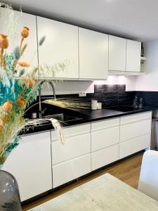 a kitchen with white cabinets and a sink at Sfeervolle vakantiewoning aan zee in Ostend