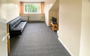 uma sala de estar com um sofá e uma televisão em Headrose House em West Bromwich