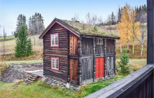 een klein houten huis met rode deuren in een veld bij Hysjulien Grd in Skåbu
