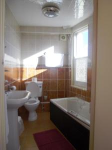 a bathroom with a tub and a toilet and a sink at Hotel de Ville in Ramsgate