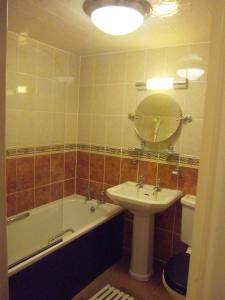 a bathroom with a tub and a sink and a mirror at Hotel de Ville in Ramsgate