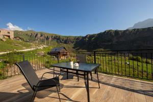 a black table and chair on a deck with a view at Hotel GENI Kazbegi in Stepantsminda