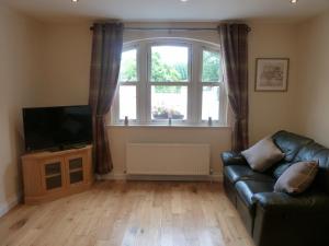 a living room with a couch and a television at Oatlands Self Catering Lets in Hillsborough