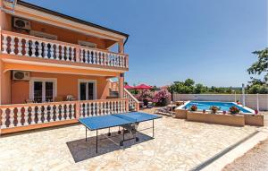 een huis met een tafel en een zwembad bij Cozy Home In Betiga With Outdoor Swimming Pool in Barbariga