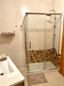 um chuveiro com uma porta de vidro na casa de banho em Arte de Marinheiro em Sesimbra