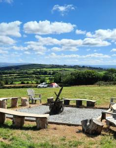 a group of picnic tables and benches in a field at Summit Camping Kit Hill Stunning views Grass pitch or upgrade to Bell tent hire in Callington