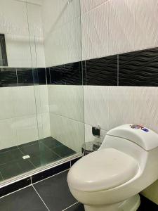 a bathroom with a white toilet and a shower at Hotel Avei Suites in Cali