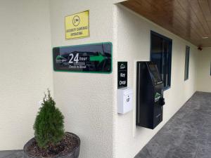 una máquina atm en el lateral de un edificio con una planta en Bassingers Motor Lodge, en Levin