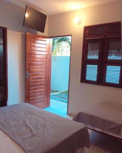 - une chambre avec 2 lits et une porte coulissante en verre dans l'établissement Aloha Kite House, à Lagoinha