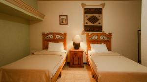 ein Schlafzimmer mit 2 Betten und einem Tisch mit einer Lampe in der Unterkunft Hotel Casa Guivá in Oaxaca de Juárez