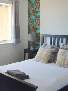a bedroom with a bed with two pillows and a window at Four Seasons by the Sea in Peacehaven