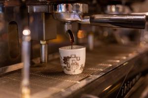 a coffee is being poured into a coffee cup at Trattoria & Apartments - Casa da Enzo in Goslar