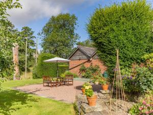 a garden with a table and chairs and an umbrella at Riverside in Craven Arms