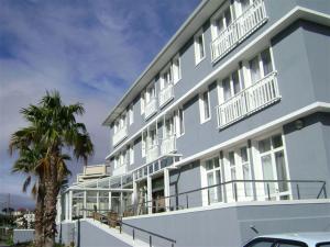 un edificio azul con balcones blancos y una palmera en The Calders Hotel & Conference Centre, en Fish Hoek