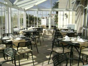 un comedor con mesas, sillas y ventanas en The Calders Hotel & Conference Centre, en Fish Hoek