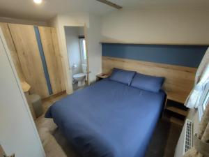 a bedroom with a blue bed and a bathroom at 3 Bedroom Luxury Caravan - Vans With Business Sign Not Allowed in Port Seton