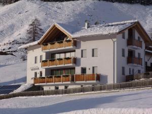 Un bâtiment blanc avec de la neige au sol dans l'établissement Residence Weisskugel Langtaufers Südtirol, à Melago