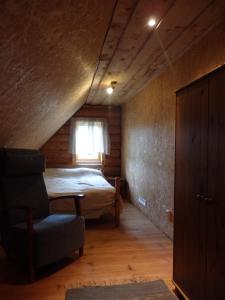 a bedroom with a bed and a chair and a window at Tigete Holiday Cottage in Lootvina