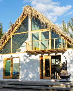 een huis met een rieten dak en een balkon bij Coconi House in Tuxpan de Rodríguez Cano