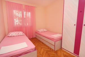 a room with two beds and a window with pink curtains at Apartments by the sea Postira, Brac - 5152 in Postira