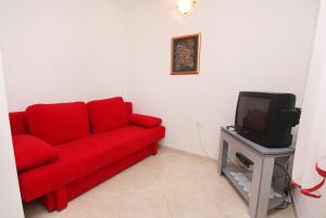 a red couch in a living room with a tv at Apartments by the sea Postira, Brac - 5152 in Postira