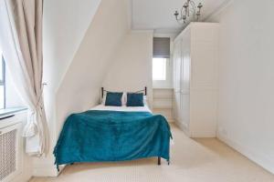 um quarto branco com uma cama com um cobertor azul em Stylish London Getaway in the Heart of the City em Londres