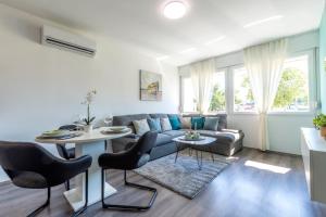 Una sala de estar con un sofá, una mesa y sillas. en New Luxury Bella Apartment, en Split