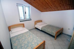 two beds in a small room with a window at Apartment Grebastica 4867a in Grebaštica