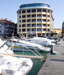 un gruppo di imbarcazioni ormeggiate in un porto turistico con un edificio di Laguna Palace Hotel Grado a Grado