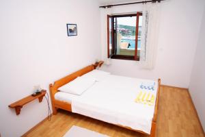 a small bedroom with a bed and a window at Apartments by the sea Jezera, Murter - 5063 in Jezera