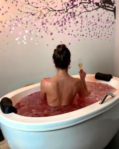 a man sitting in a bath tub with a glass of wine at Lofts Urbano in Urubici