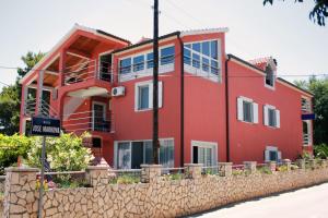 une maison rouge avec une clôture en pierre devant elle dans l'établissement Apartments with a parking space Murter - 5084, à Murter