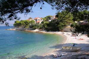 a beach with people and a boat on the shore at Apartments by the sea Postira, Brac - 5660 in Postira