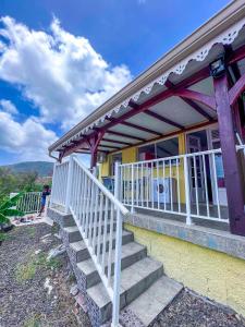 une maison jaune avec des escaliers menant à une terrasse couverte dans l'établissement Ocean bleu 972 Orange N 2, à Les Anses-d'Arlet