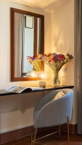 SPIRIT OF FLORENCE Boutique Rooms في فلورنسا: مكتب مع إناء من الزهور ومرآة