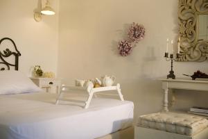 a bedroom with a white bed with a chair and candles at Althea Traditional Hotel in Alonnisos