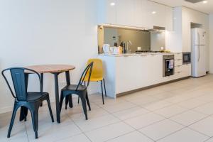 La cuisine est équipée d'une table, de chaises et d'un réfrigérateur. dans l'établissement Chic Inner City Position 2 bedroom apartment with Parking By Serain Residences, à Brisbane