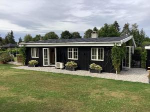 um barracão preto com janelas brancas e um quintal em Holiday home Gilleleje LXXXVIII em Gilleleje