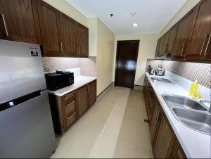 uma cozinha com armários de madeira, um lavatório e um frigorífico em Anvaya Cove Short Term Rental Condos em Morong