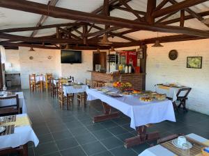 a dining room with tables and chairs and a kitchen at Chales Bela Serra in Monte Verde